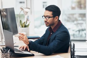 Man in an office working on a laptop, demonstrating the efficiency of automating payroll tasks with modern technology.