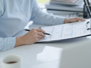 Business professional reviewing financial documents on a clipboard, focusing on tax deductions for small business.