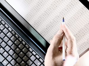 Close-up of a person analysing a spreadsheet on a laptop, focusing on tax deductions for small business.