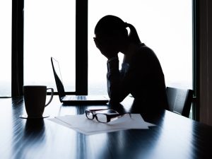 A stressed woman dealing with tax penalties at her desk, highlighting tax challenges faced by small businesses.